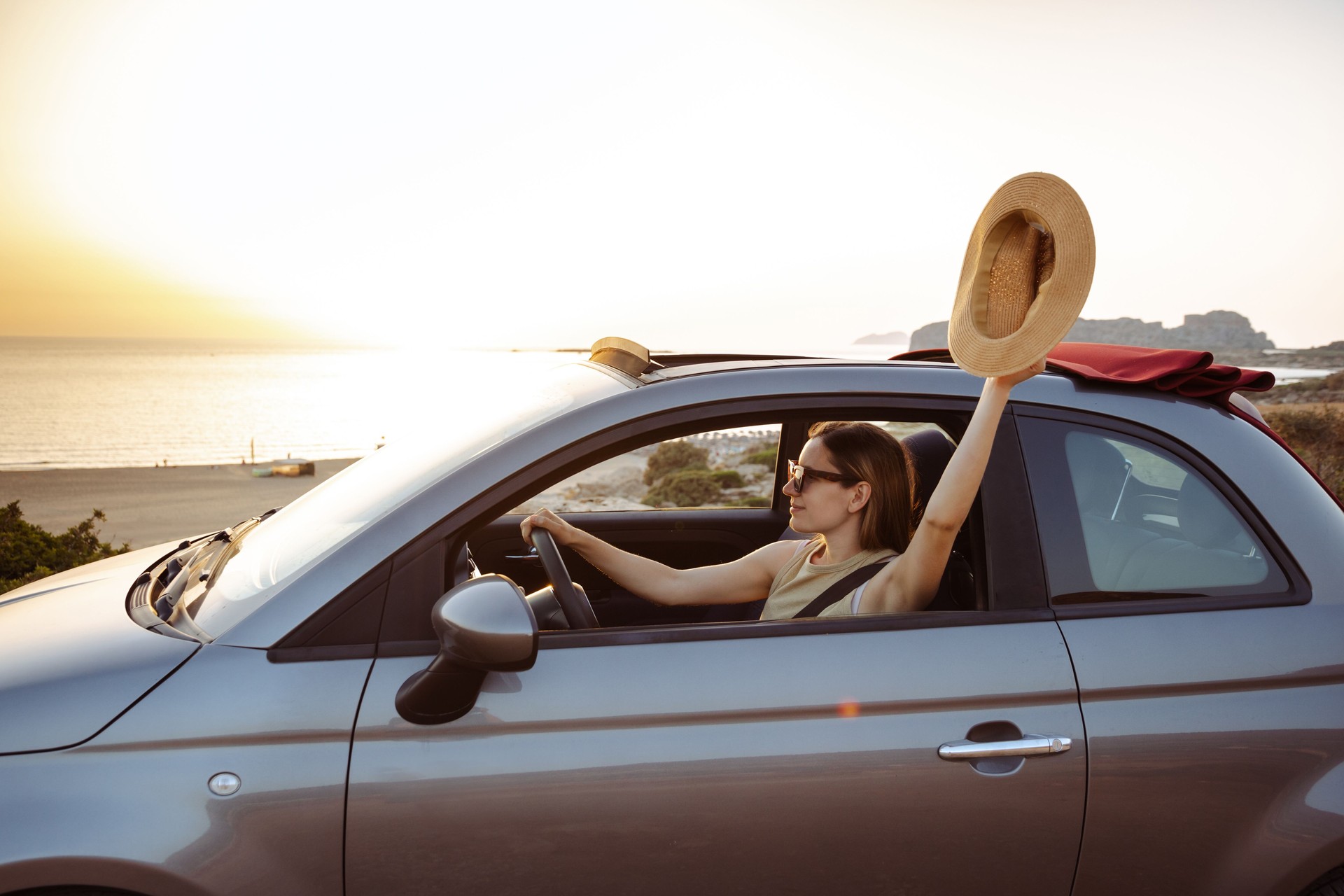 Young woman is driving a convertible car and enjoying a summer day